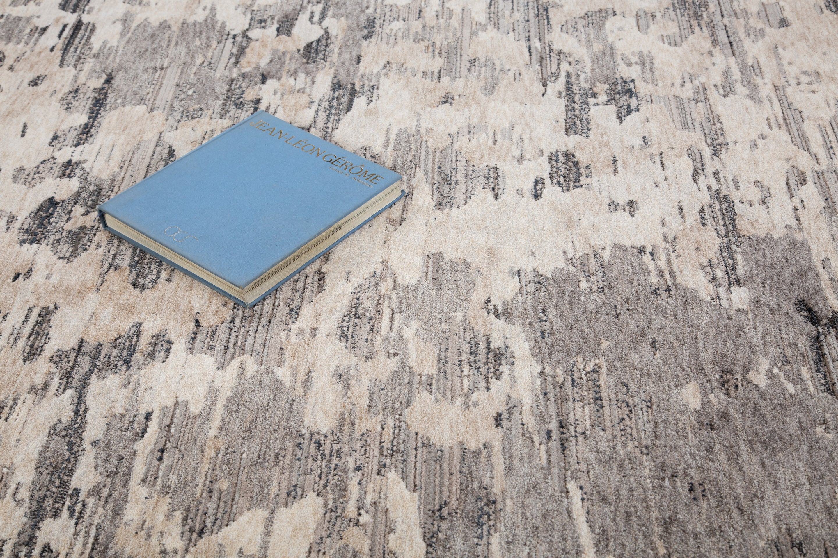 Blue book on gray and white striped wool rug with textured surface
