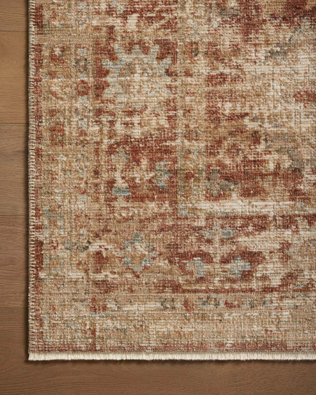 Vintage-style rug with faded terracotta and beige distressed floral pattern throughout