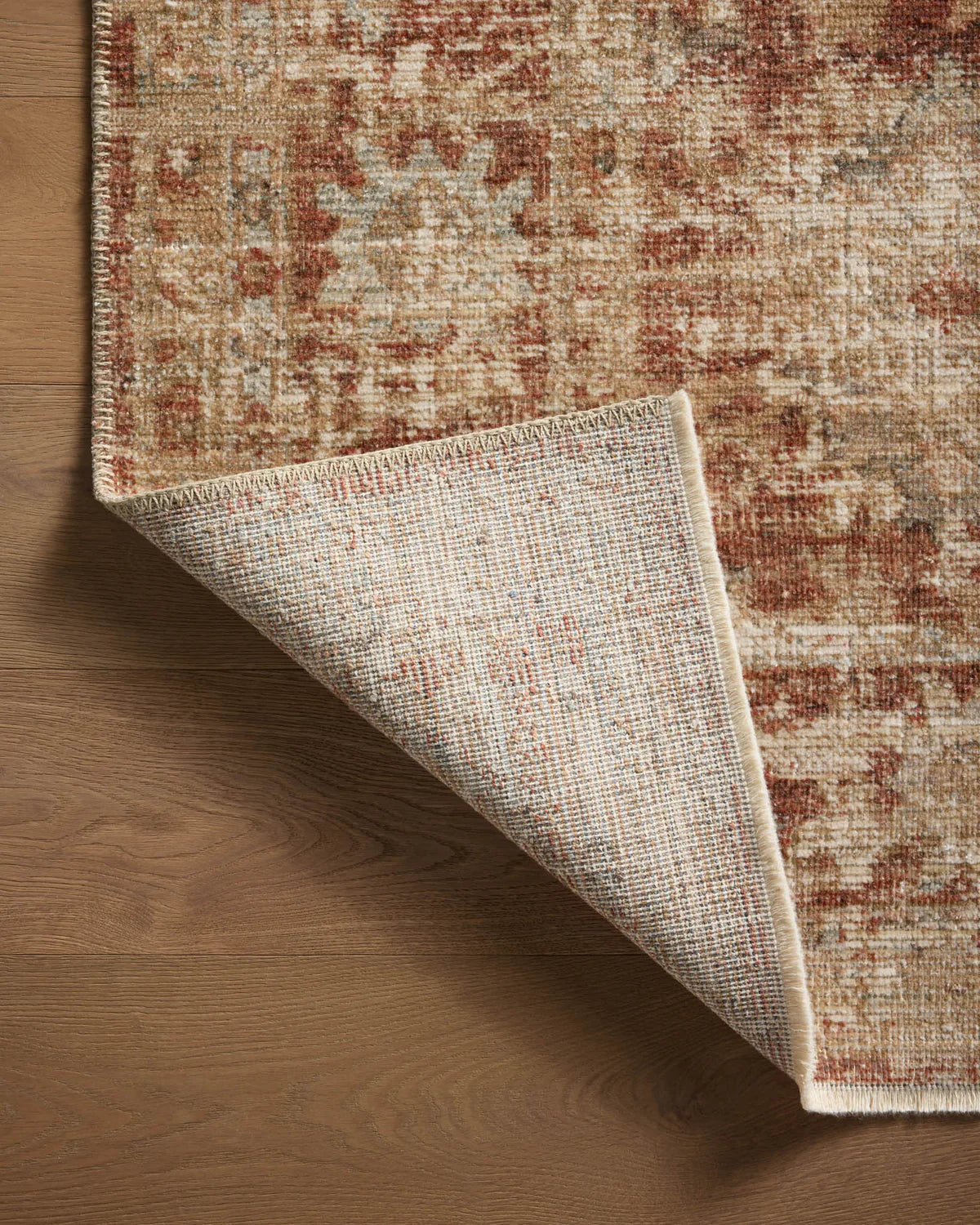 Vintage-style rug with faded terracotta and beige distressed floral pattern throughout