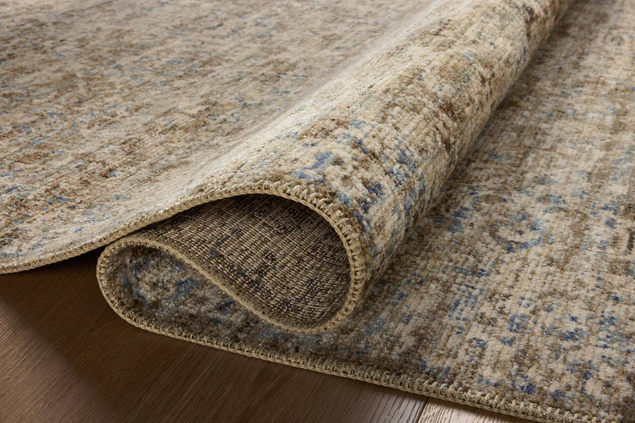 Vintage-style area rug with faded blue and beige geometric patterns throughout