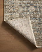 Vintage-style area rug with faded blue and beige geometric patterns throughout