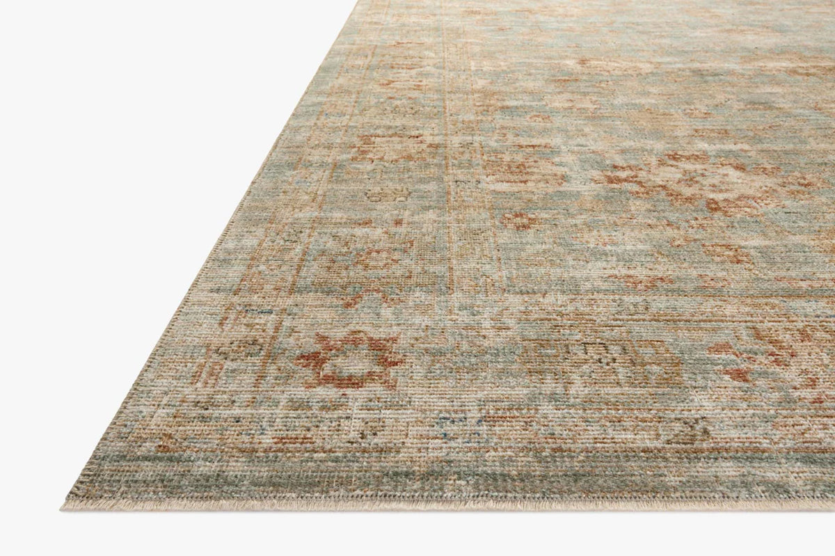 Vintage-style rug with faded rust and cream patterns on soft green background