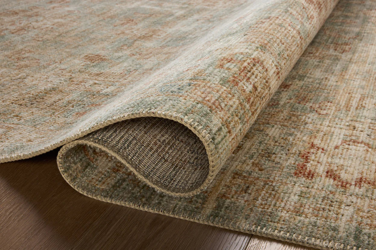 Vintage-style rug with faded rust and cream patterns on soft green background