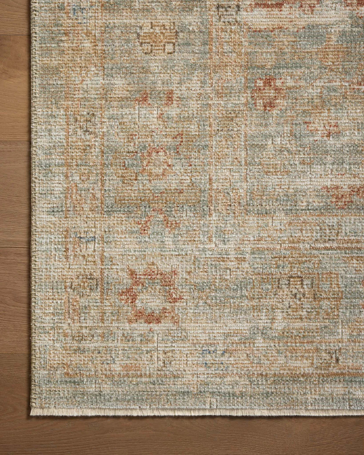Vintage-style rug with faded rust and cream patterns on soft green background