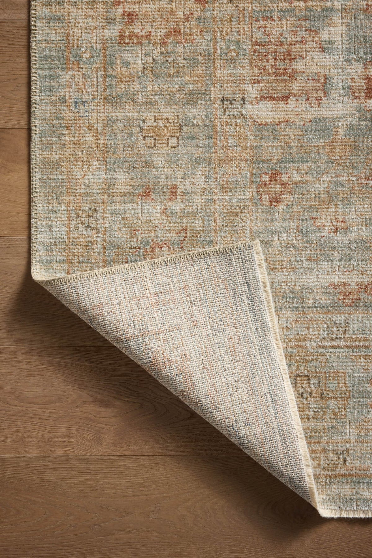 Vintage-style rug with faded rust and cream patterns on soft green background