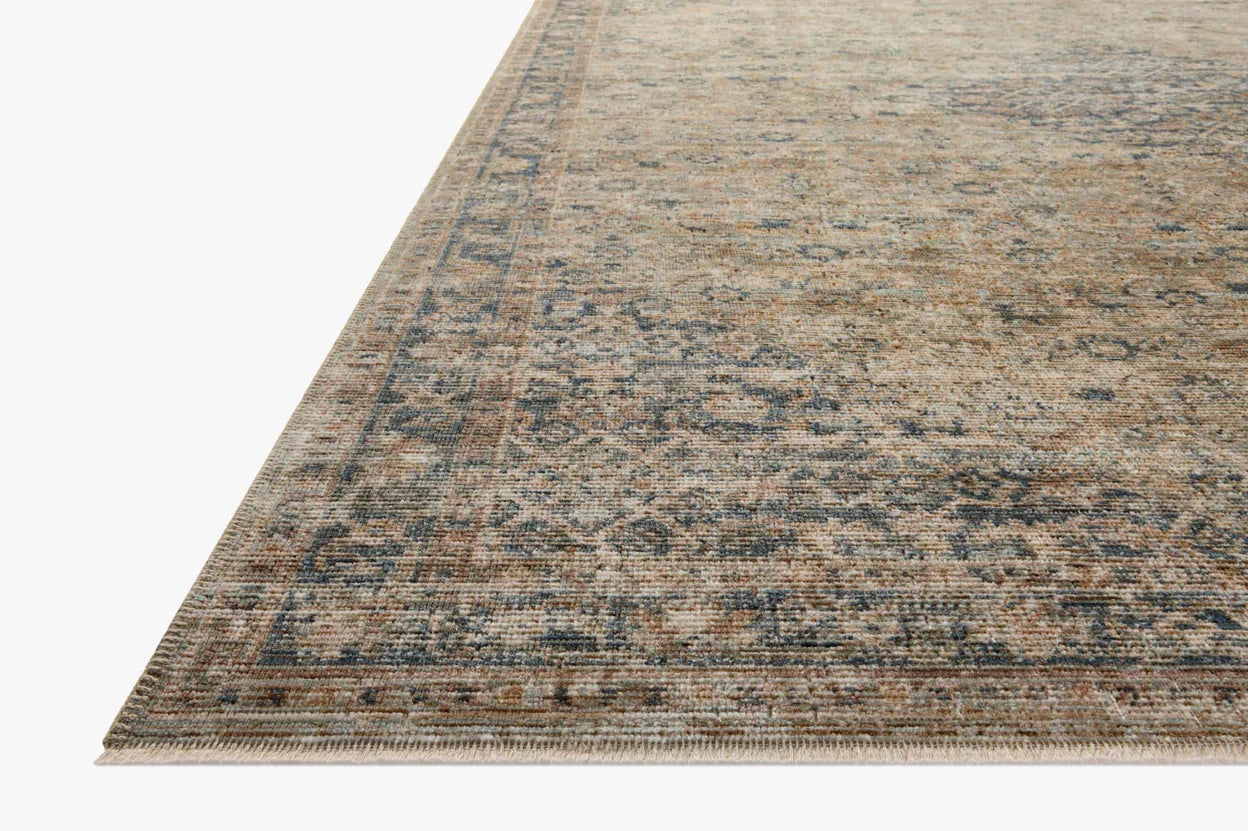 Vintage-style area rug with faded blue and beige geometric patterns throughout