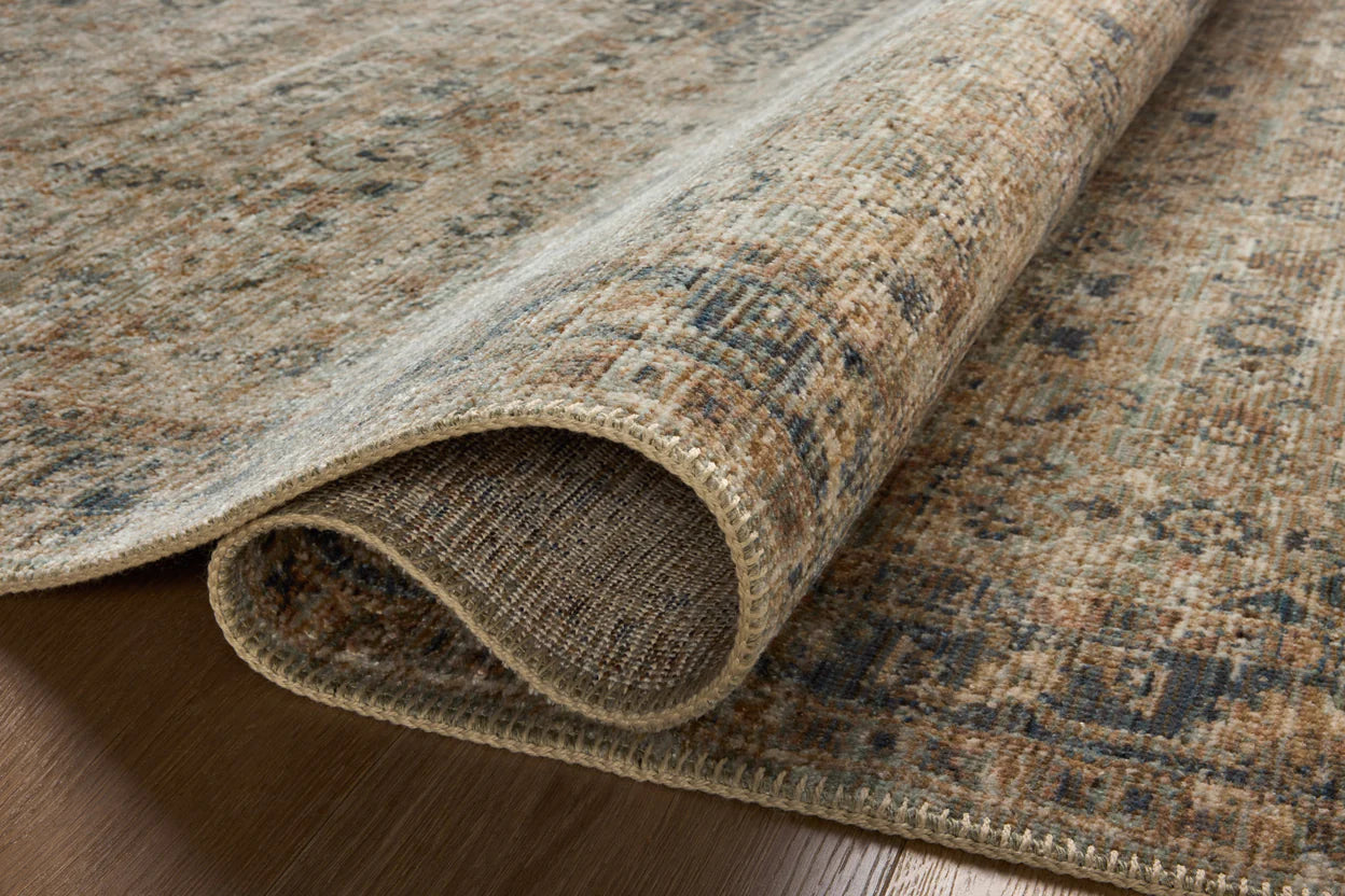 Vintage-style area rug with faded blue and beige geometric patterns throughout