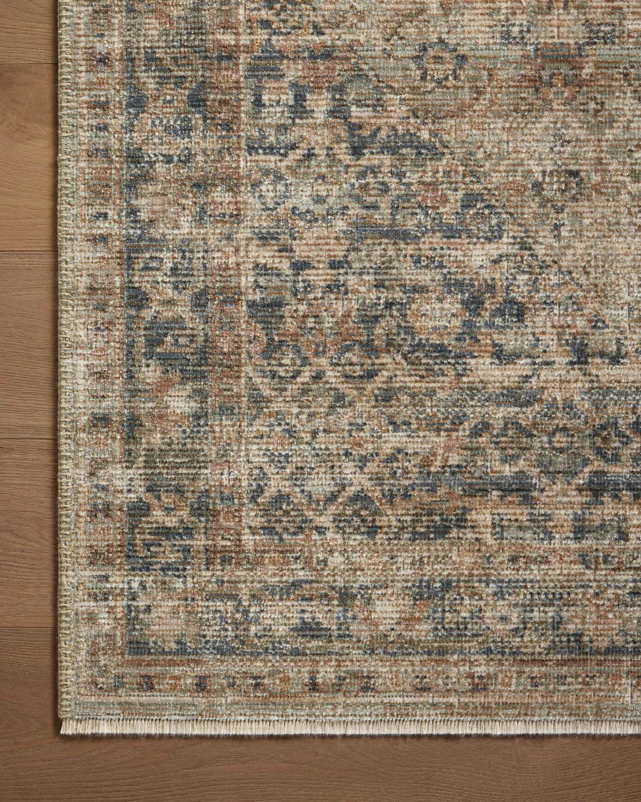Vintage-style area rug with faded blue and beige geometric patterns throughout