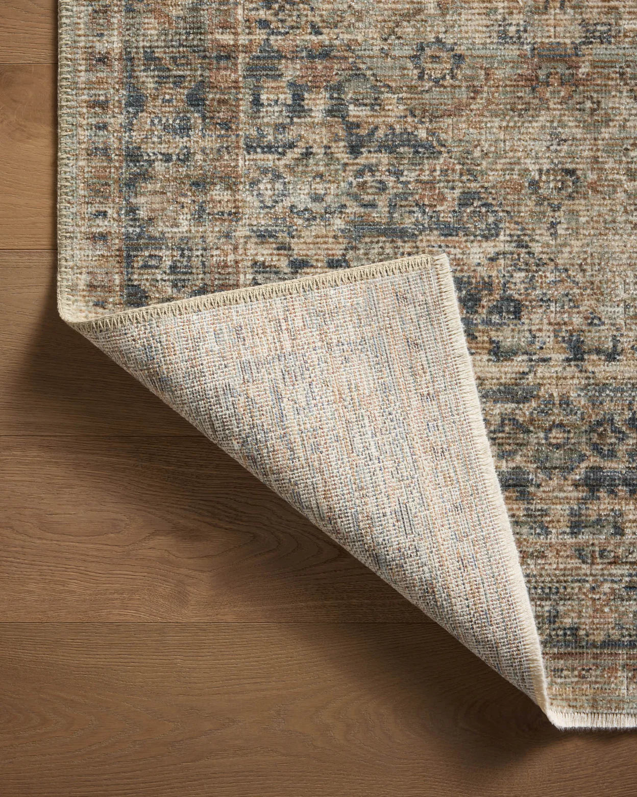Vintage-style area rug with faded blue and beige geometric patterns throughout
