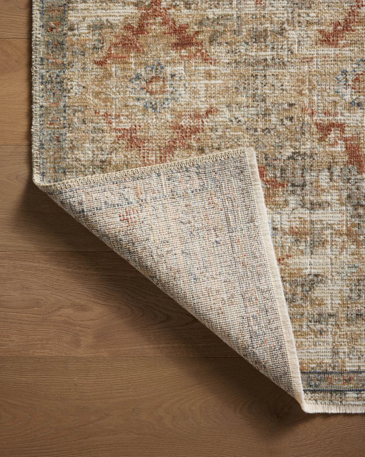 Vintage-style area rug with distressed red and beige geometric patterns on neutral background