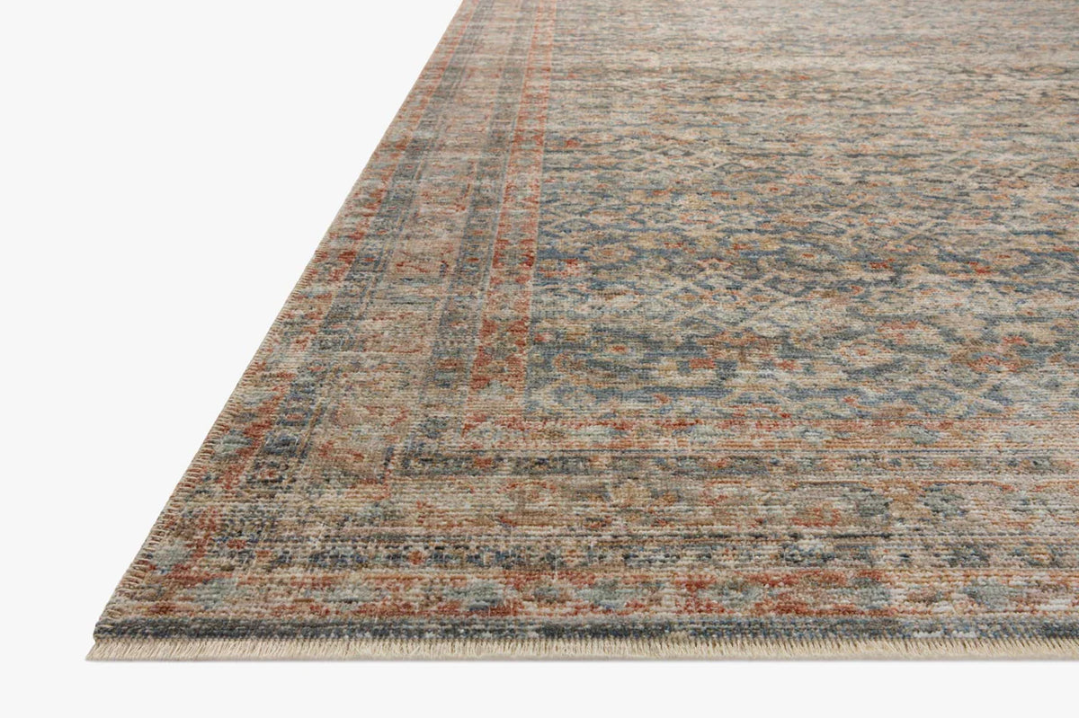 Vintage-style rug with intricate geometric patterns in blue, rust and cream tones