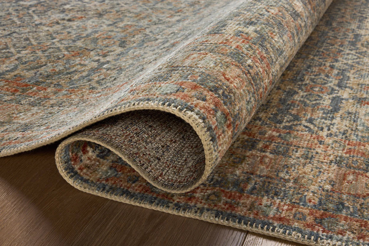 Vintage-style rug with intricate geometric patterns in blue, rust and cream tones
