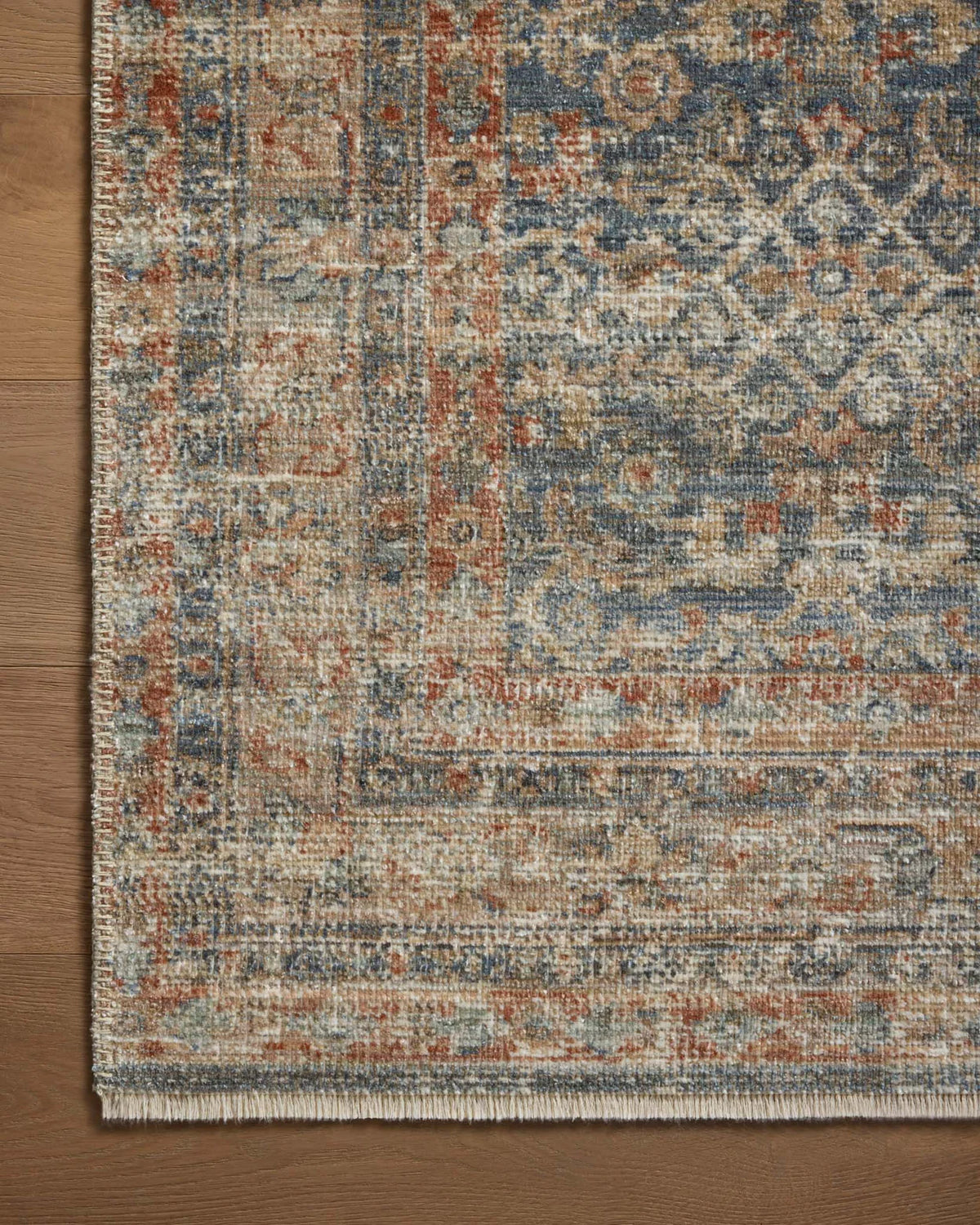 Vintage-style rug with intricate geometric patterns in blue, rust and cream tones