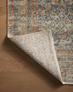 Vintage-style rug with intricate geometric patterns in blue, rust and cream tones