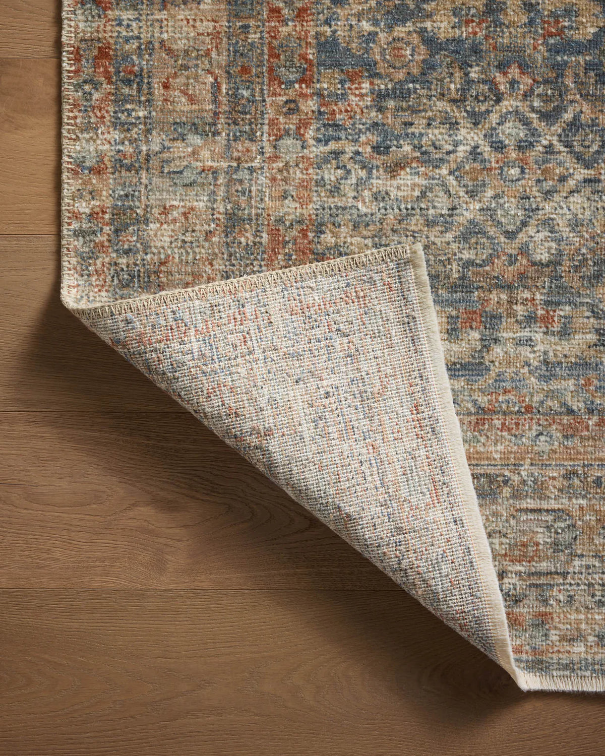 Vintage-style rug with intricate geometric patterns in blue, rust and cream tones