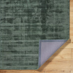 Sage green distressed rug with textured, mottled surface and worn vintage appearance