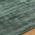 Sage green distressed rug with textured, mottled surface and worn vintage appearance