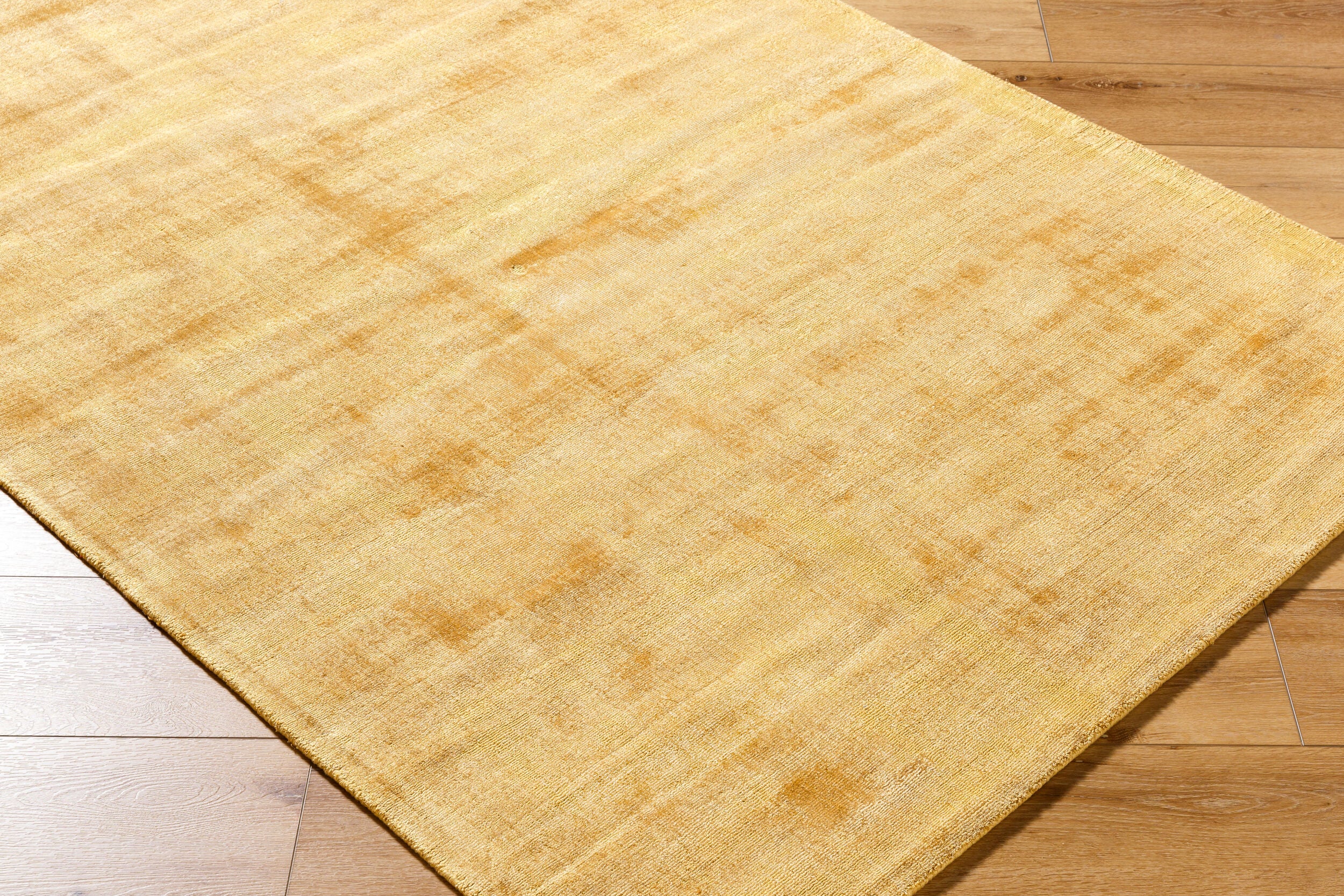 Golden beige textured area rug with subtle worn distressed pattern throughout