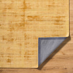 Golden beige textured area rug with subtle worn distressed pattern throughout