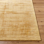 Golden beige textured area rug with subtle worn distressed pattern throughout