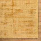 Golden beige textured area rug with subtle worn distressed pattern throughout