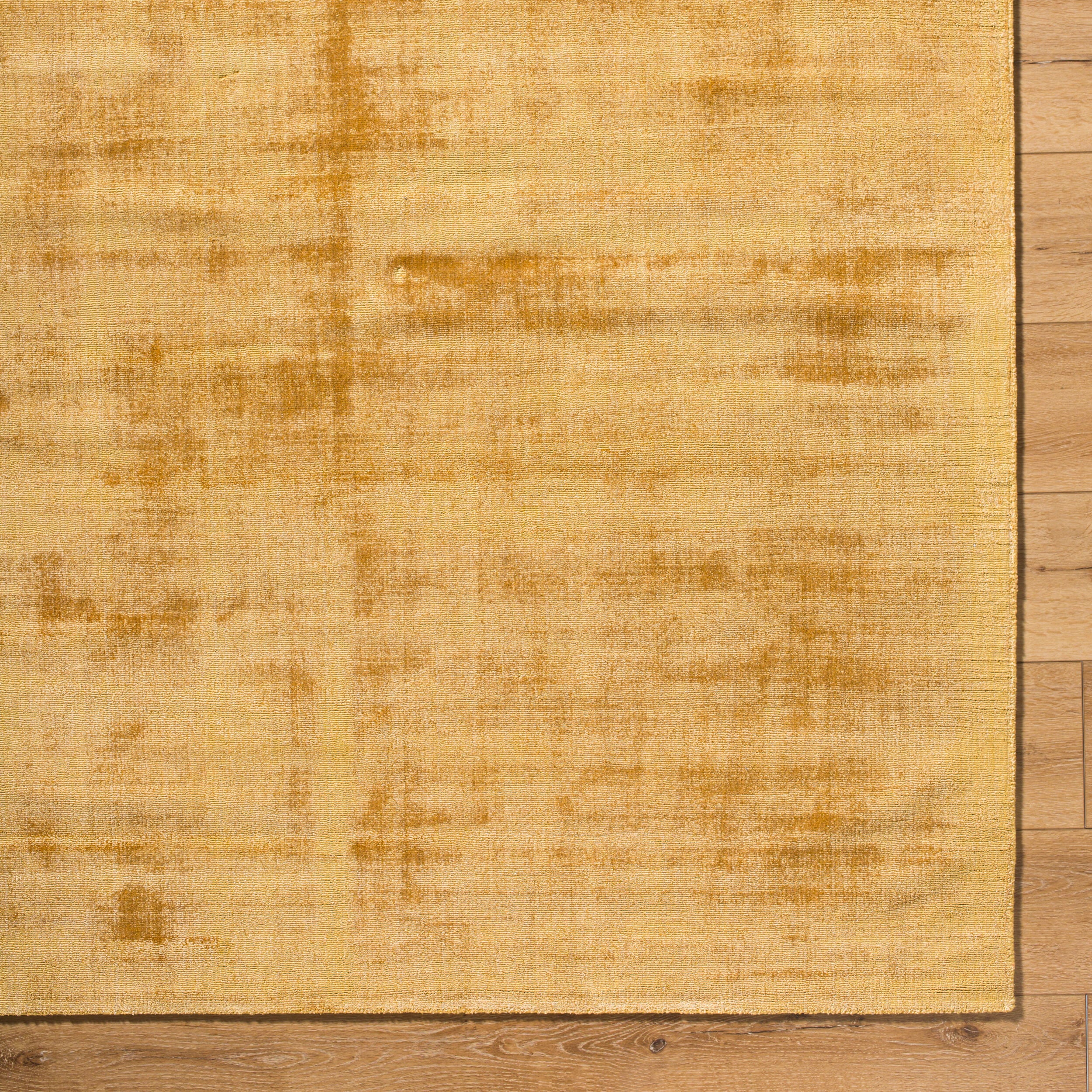 Golden beige textured area rug with subtle worn distressed pattern throughout