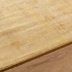 Golden beige textured area rug with subtle worn distressed pattern throughout
