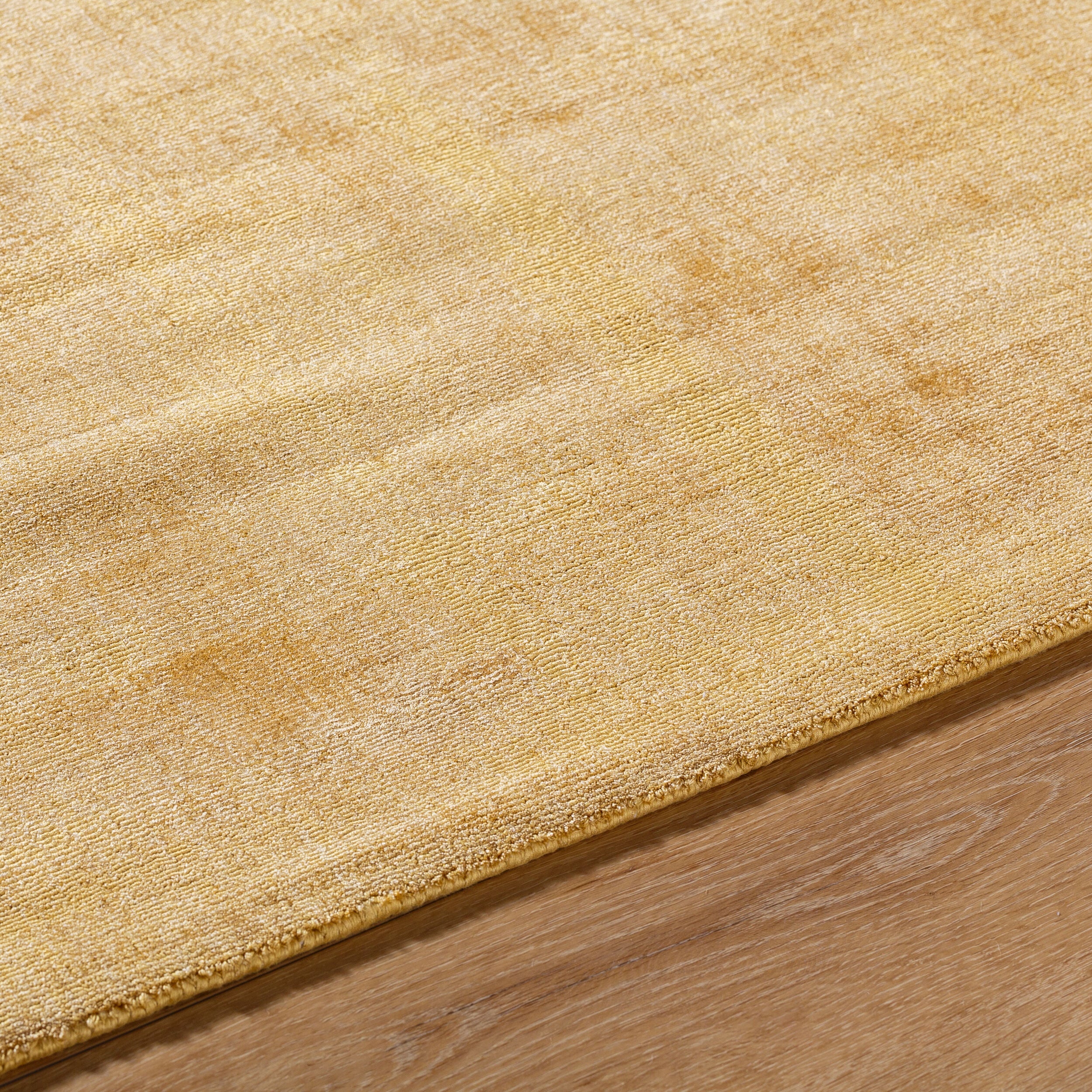 Golden beige textured area rug with subtle worn distressed pattern throughout