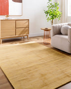 Golden beige textured area rug with subtle worn distressed pattern throughout
