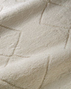 Cream quilted diamond pattern wool area rug with subtle texture