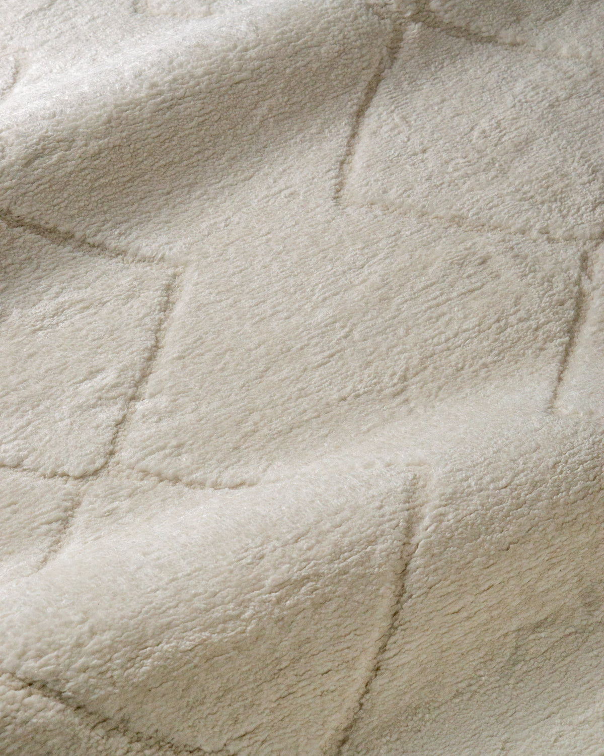 Cream quilted diamond pattern wool area rug with subtle texture