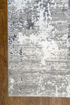 Distressed grey and white abstract area rug with weathered texture pattern