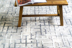 Modern geometric patterned rug in grey, white and blue tones with abstract design
