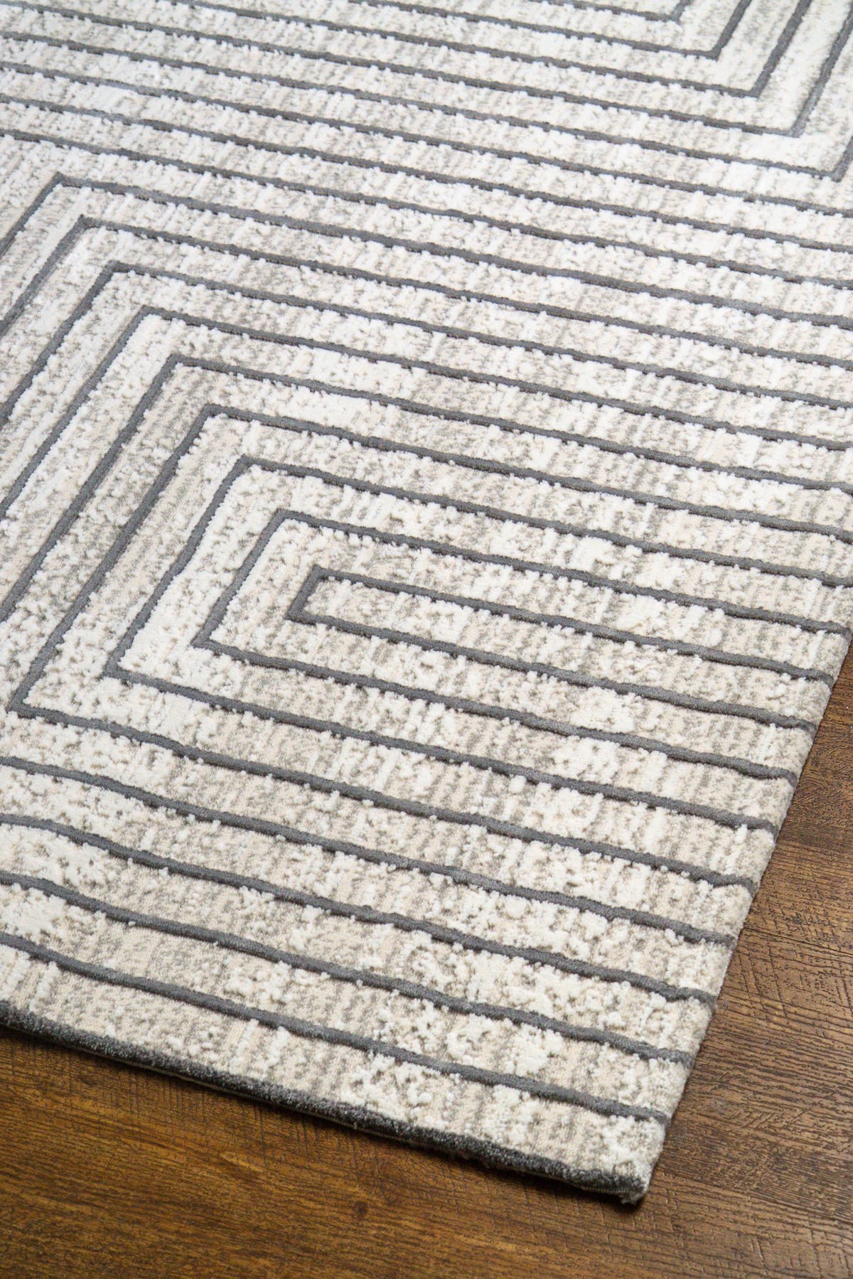 Modern geometric rug with nested square pattern in grey and cream tones