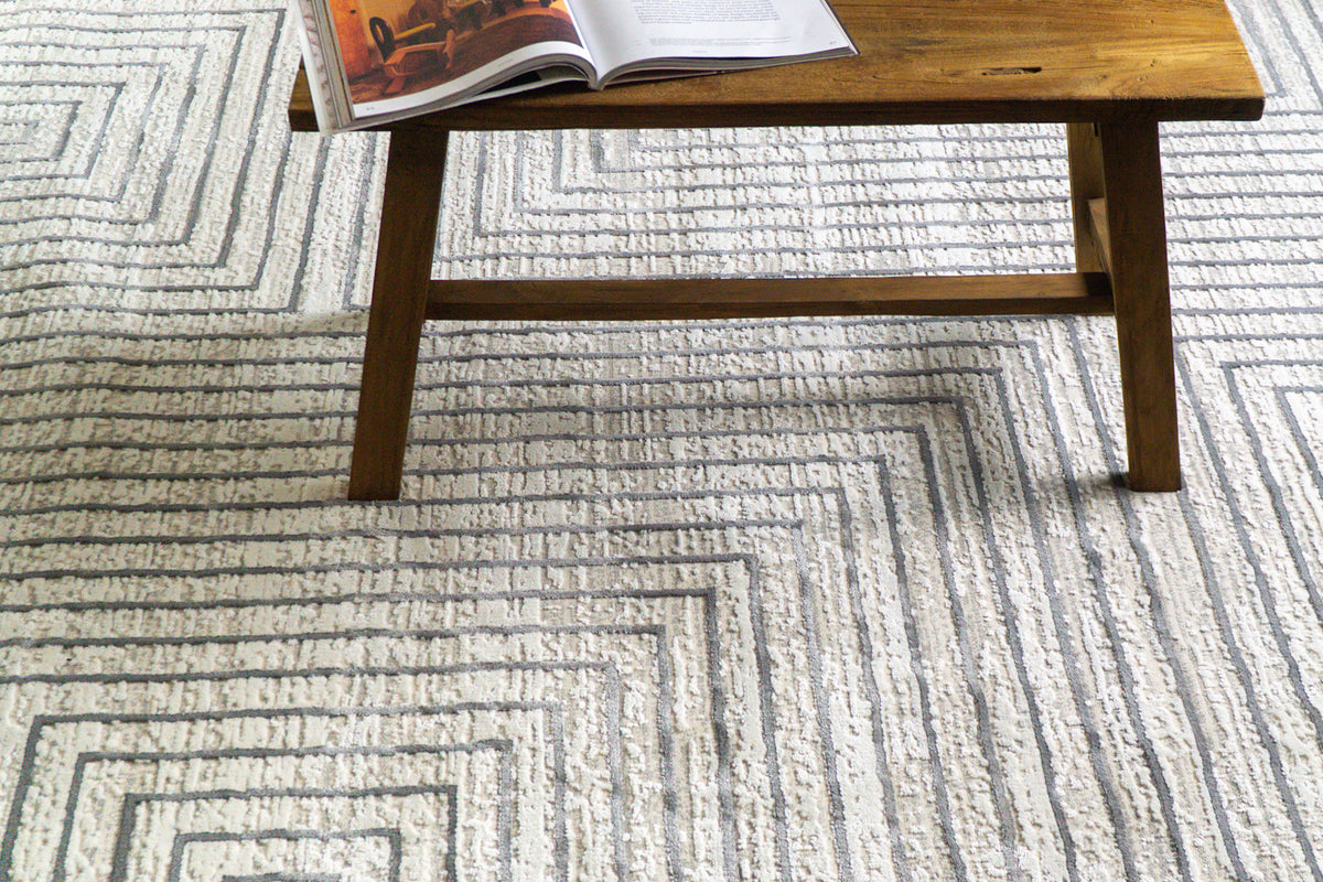 Modern geometric rug with nested square pattern in grey and cream tones