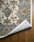 Cream and blue traditional rug with geometric diamond patterns and ornate border