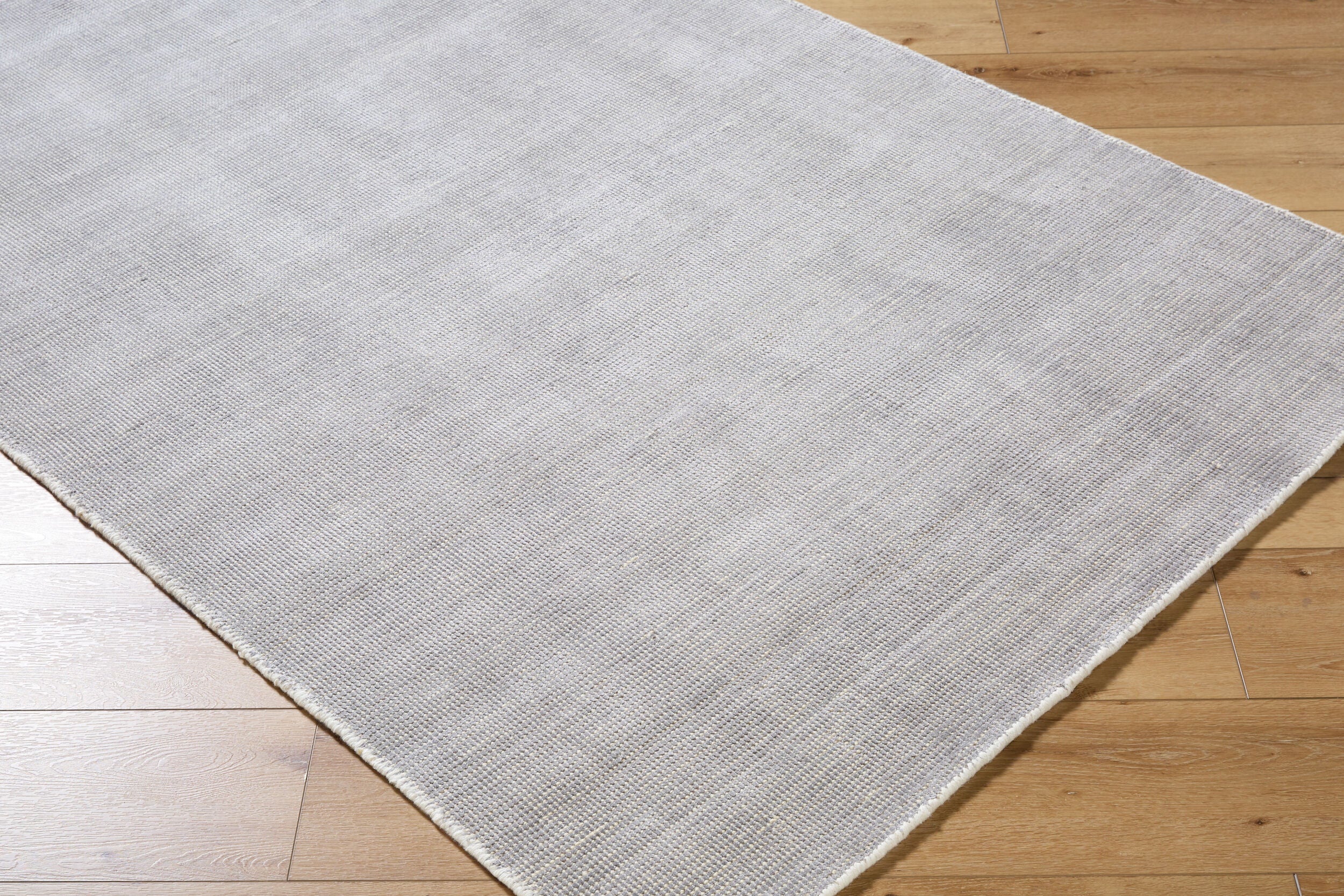 Neutral grey woven rug with subtle textured pattern and fringed edges