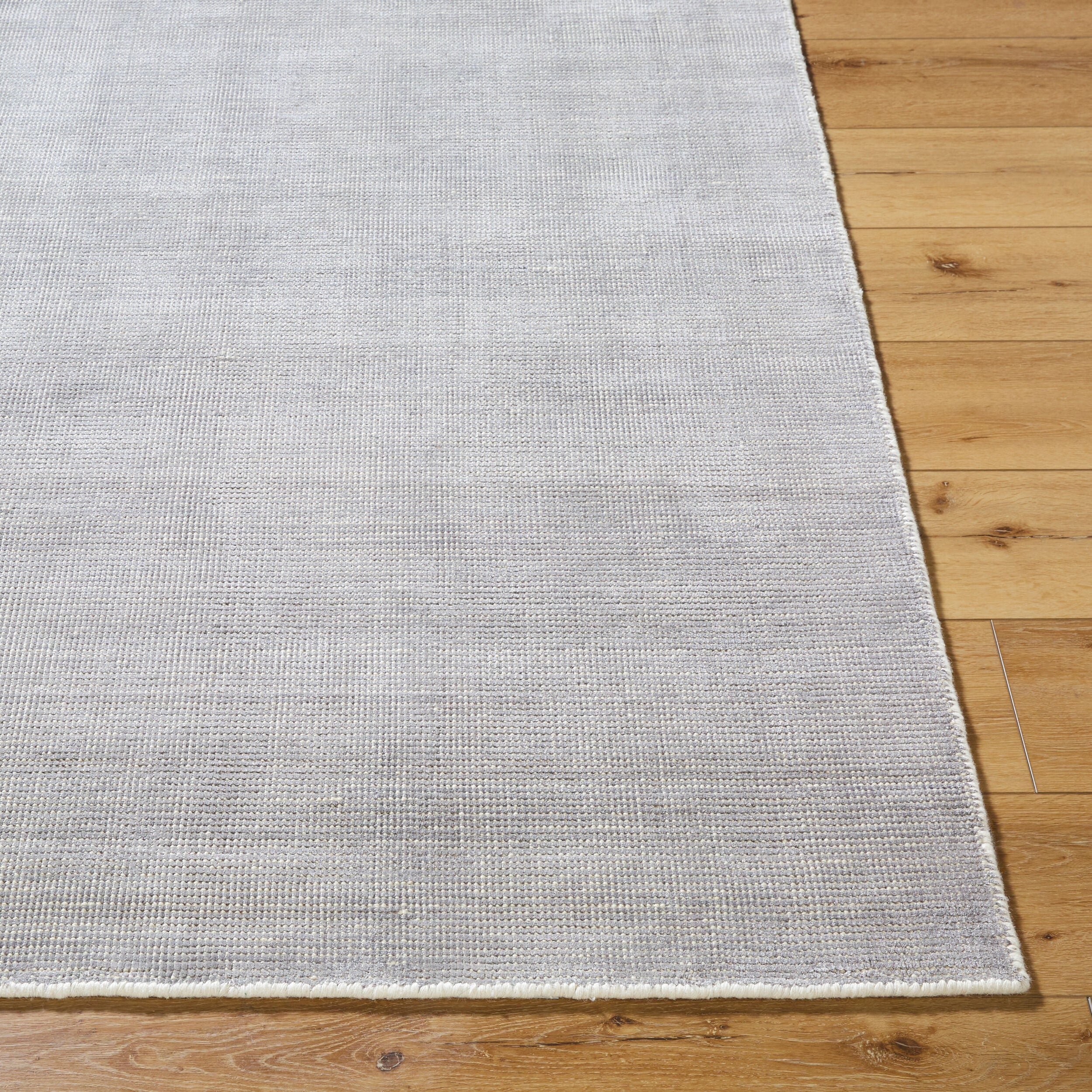Neutral grey woven rug with subtle textured pattern and fringed edges