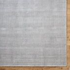 Neutral grey woven rug with subtle textured pattern and fringed edges