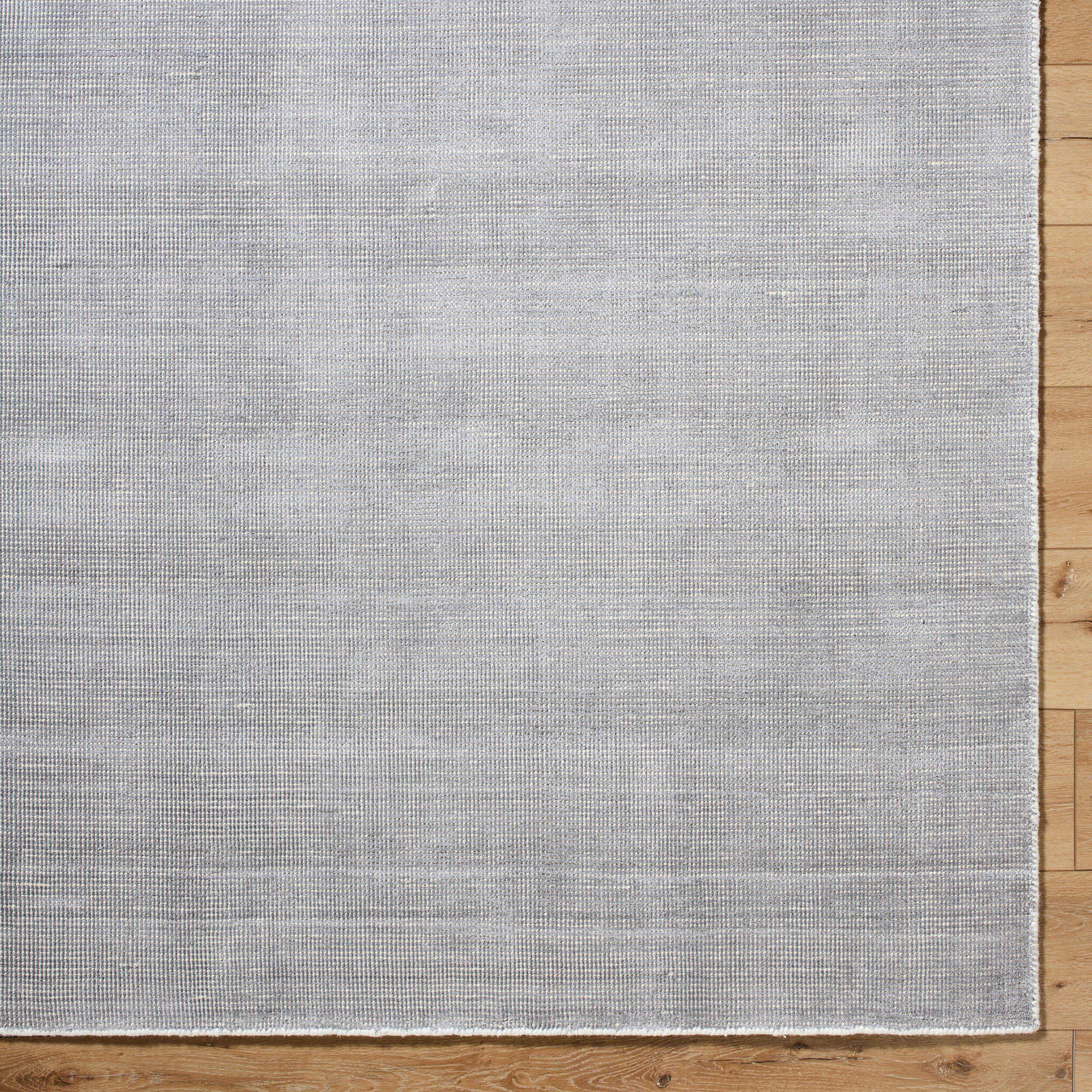 Neutral grey woven rug with subtle textured pattern and fringed edges