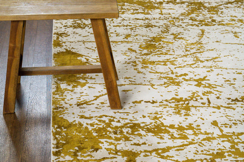 Distressed gold and cream area rug with vintage worn texture pattern