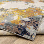 Abstract distressed rug with yellow, blue, and cream paint splatter pattern design