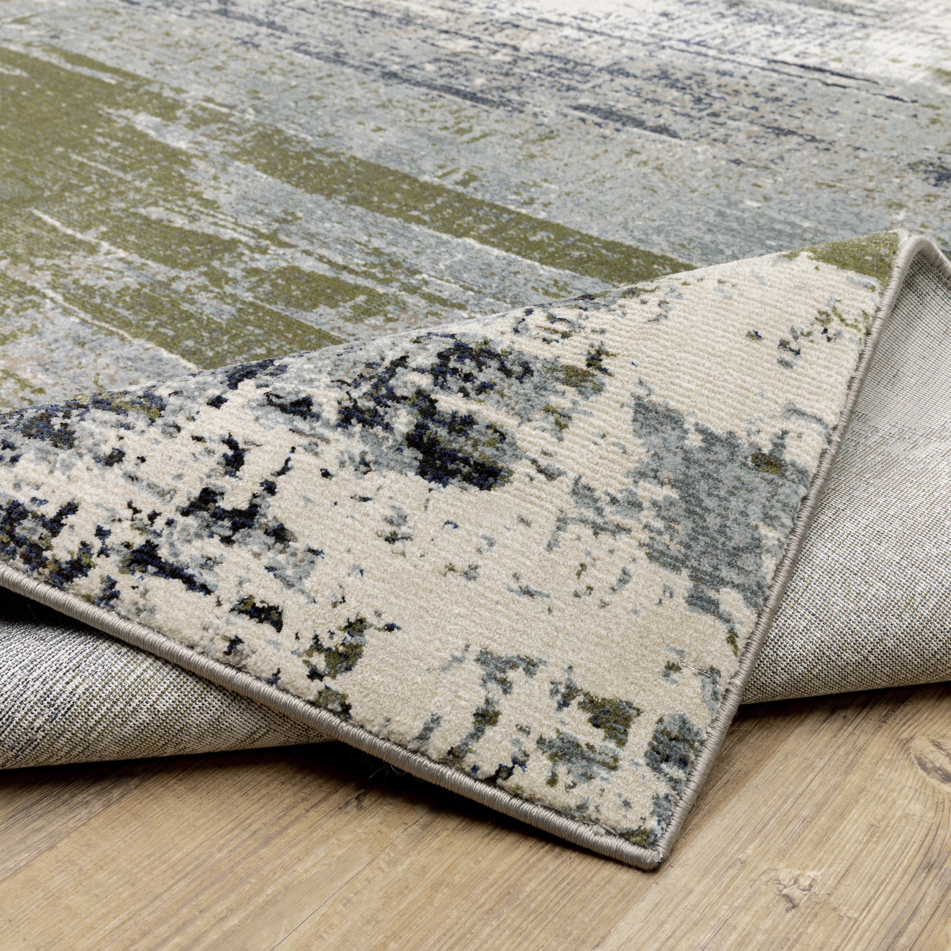 Abstract distressed area rug with grey, olive, and cream mottled texture pattern