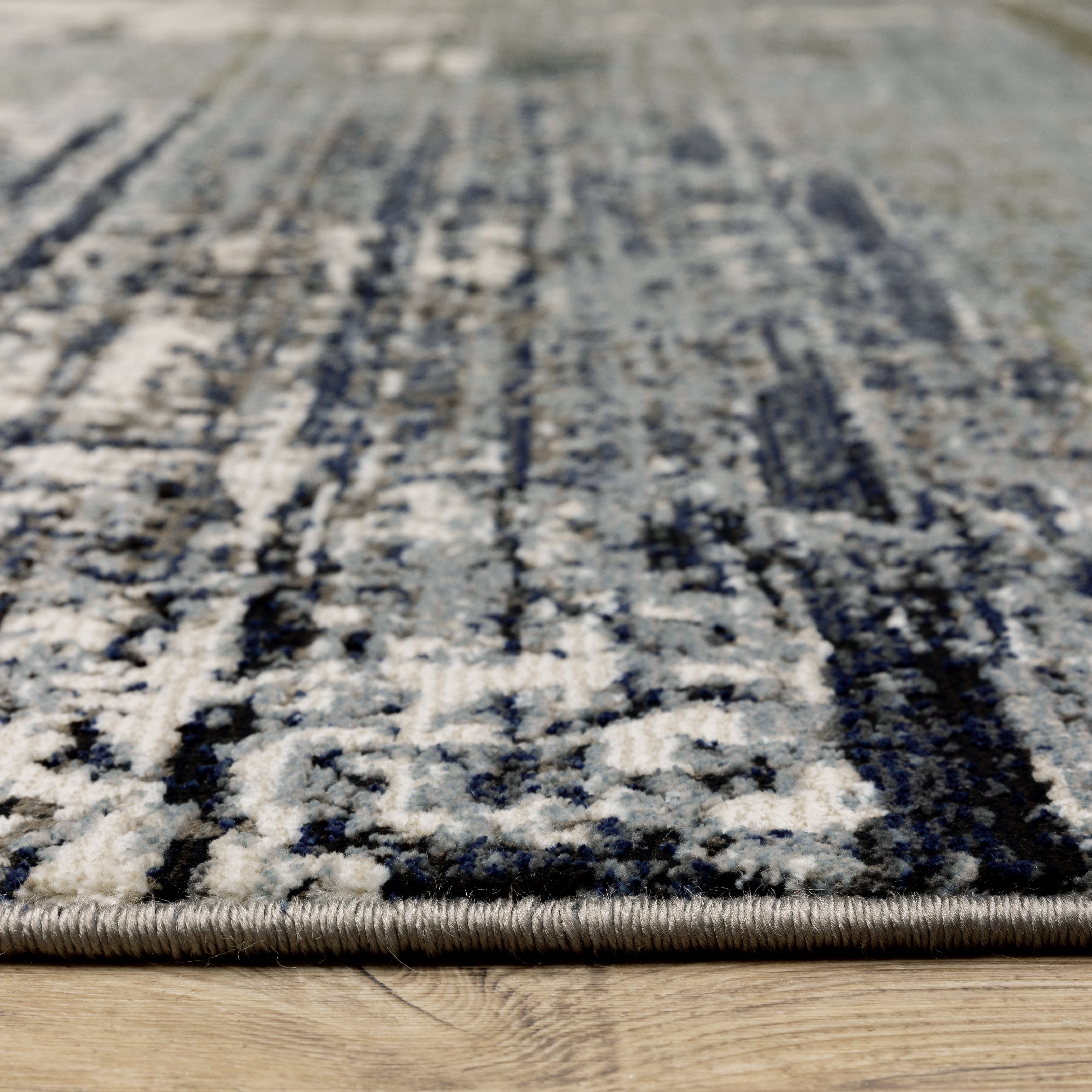 Abstract distressed area rug with grey, olive, and cream mottled texture pattern
