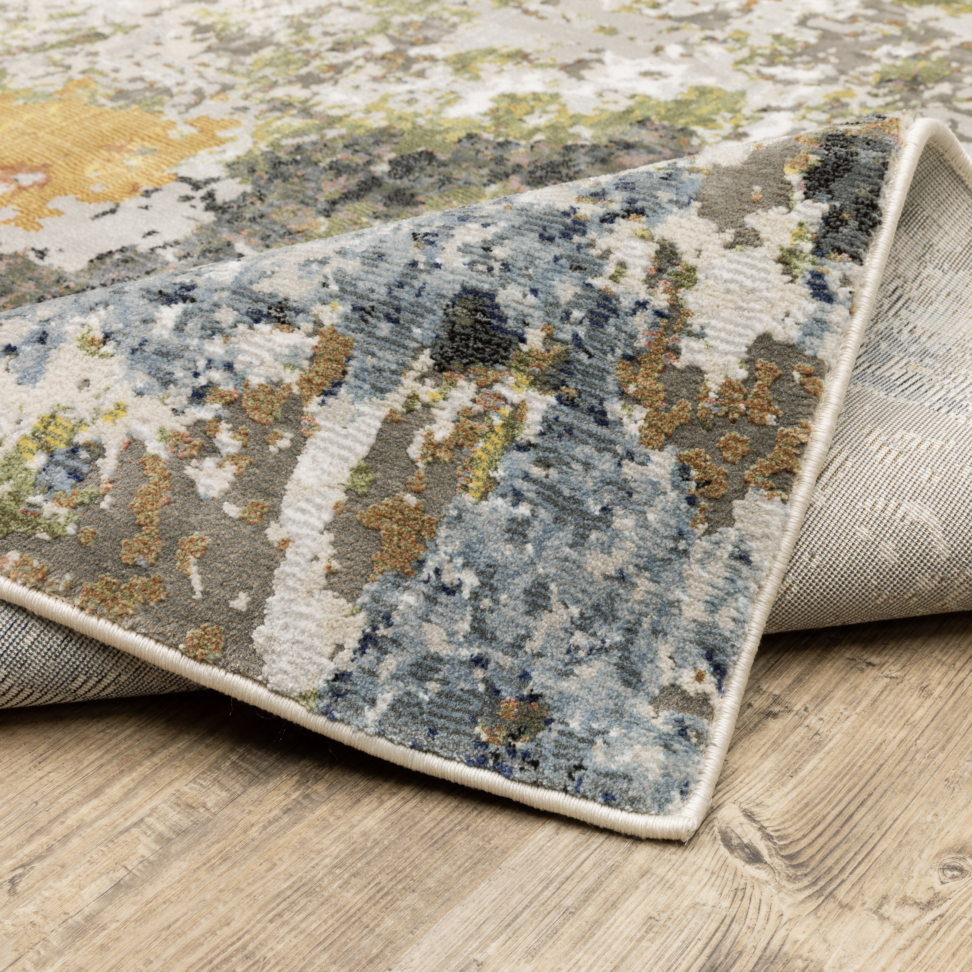 Modern abstract area rug with distressed gold, gray, and blue speckled pattern
