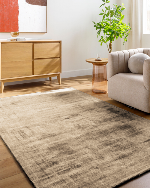 Beige distressed area rug with abstract dark streaks and worn texture throughout