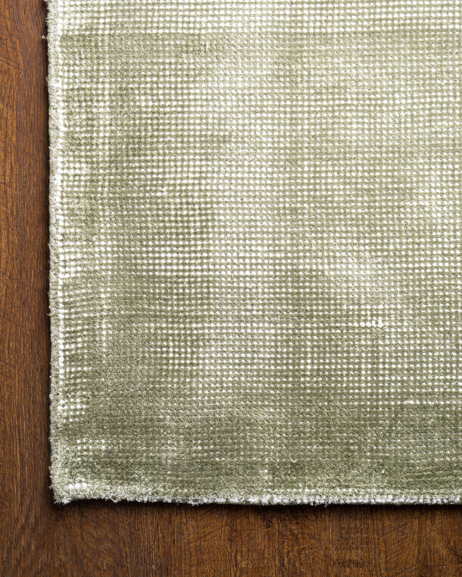 Sage green textured velvet rug with subtle worn vintage distressing throughout