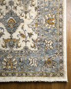 Cream and blue traditional rug with geometric diamond patterns and ornate border