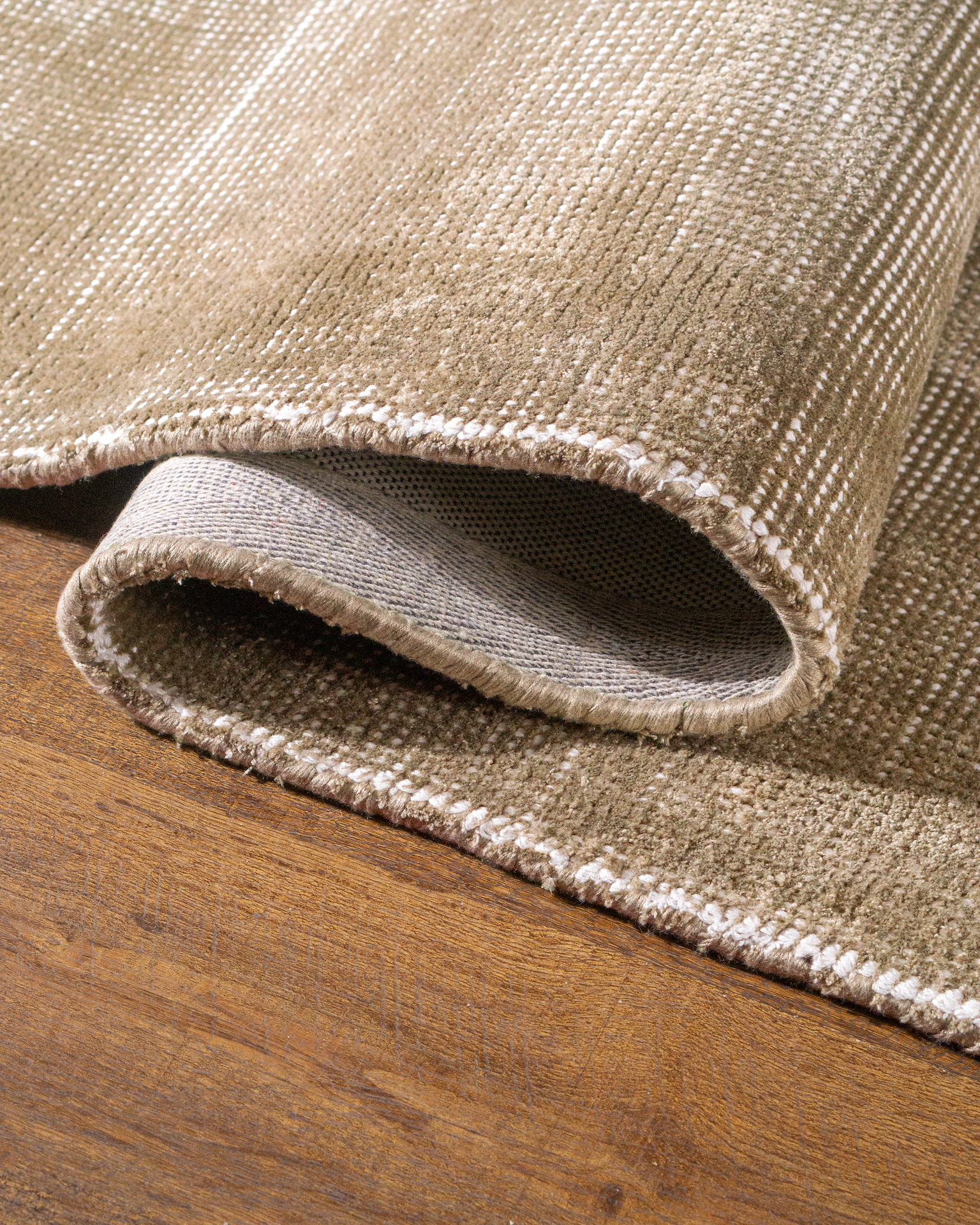 Beige textured rug with subtle horizontal striations and soft woven finish