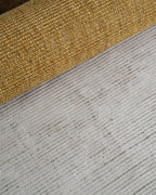 Natural woven jute rug with tight ribbed texture in golden tan color